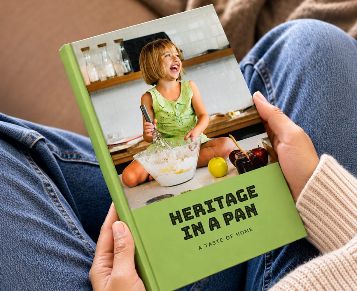 Green 'Heritage in a Pan' cookbook held in someone's lap
